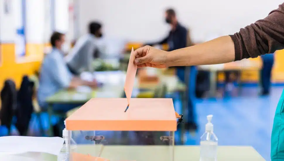 person voting by putting envelope into box