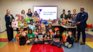 Students from the YMCA's BASE program are pictured with the donations they collected on behalf of local organizations.