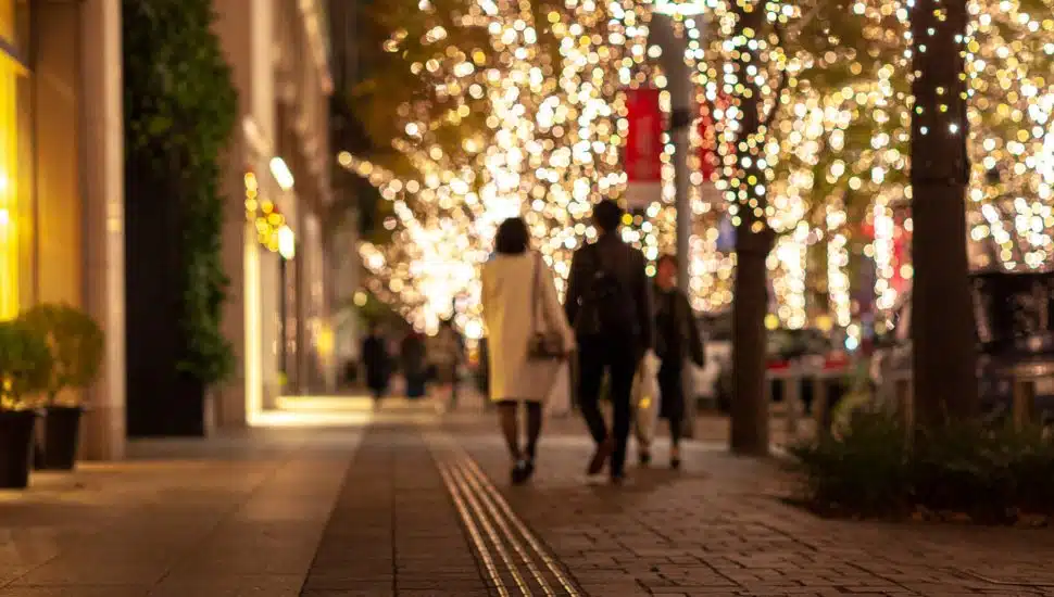 couple walks on street along holiday lights