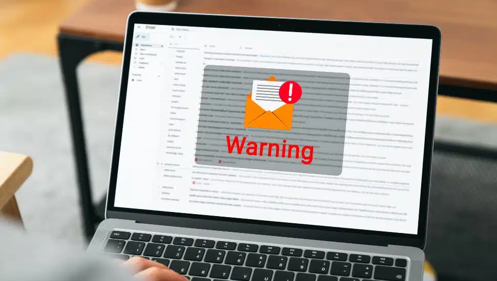 Hand using laptop with shows a warning screen of new email notifications, hack password and personal data. Concept of phishing