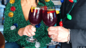 two people clinking glasses while wearing christmas clothing