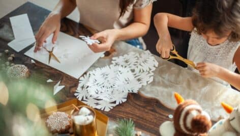 kids cut snowflakes from white paper. Gingerbread and cocoa with marshmallows. The concept of preparation for the New Year and Christmas.