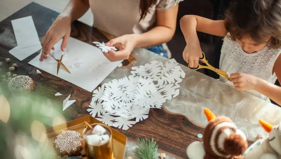 kids cut snowflakes from white paper. Gingerbread and cocoa with marshmallows. The concept of preparation for the New Year and Christmas.