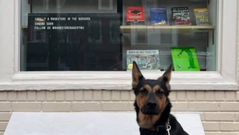 The couple's pup, Coffee, sits in front of the window of the Bookstore Bakery.