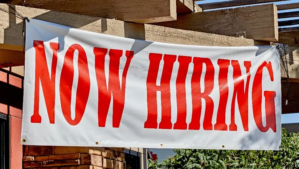 Now Hiring Banner hanging at a job site.