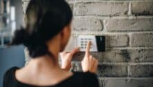 Young woman entering security pin on home alarm keypad. Home security system