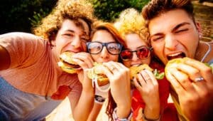 A group of teens eating burgers.