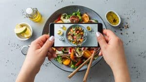 person holding a phone (taking a picture) over their salad.