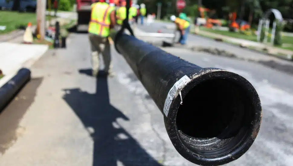 photo of Aqua worker holding pipe, indicating construction/project.