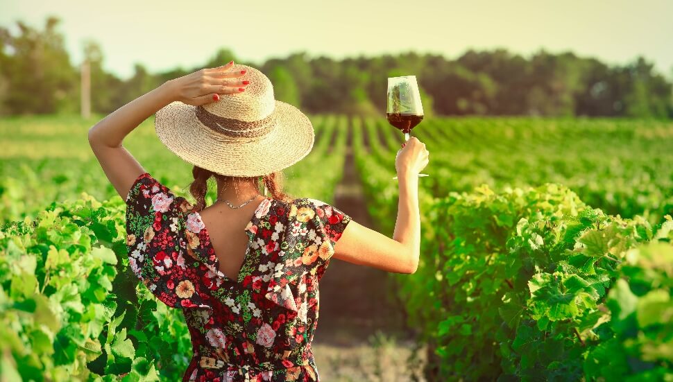 Woman raining a glass of wine in a vineyard
