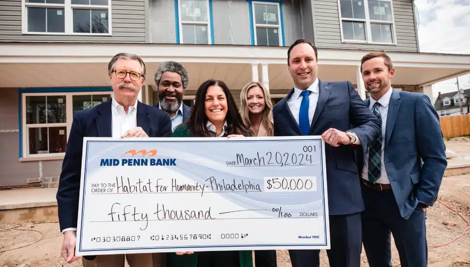 Group of people holding giant check in front of Habitat for Humanity