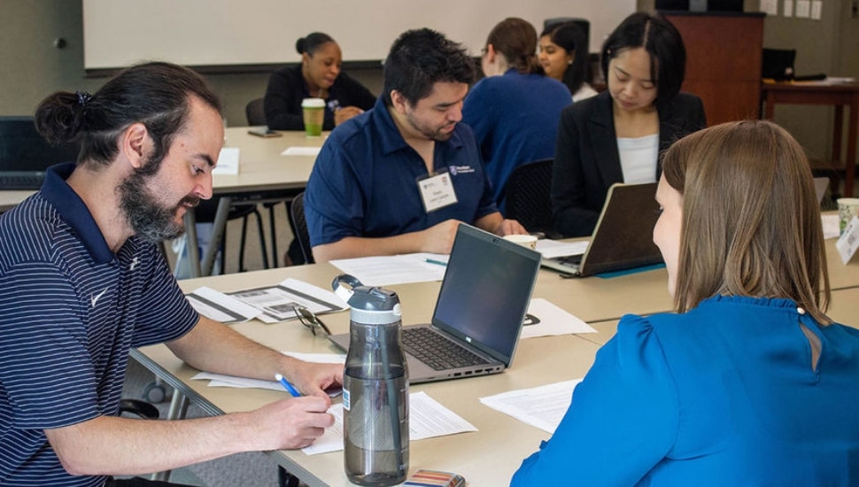 Group of graduate students and postdoc students gathered at table.
