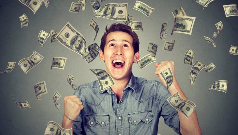 man looking at money raining down