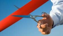 Red ribbon cutting with a pair of scissors for the inauguration of the new business activity