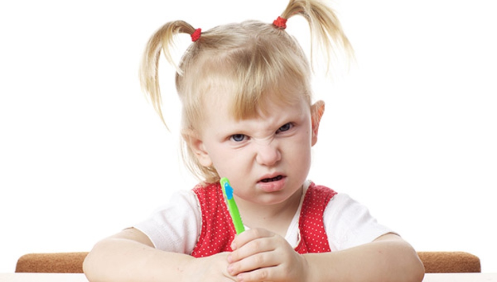 displeased child with toothbrush in hands