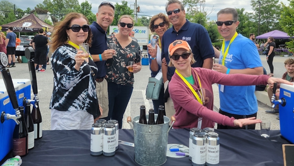 Attendees of the HFHCC's annual Hops for Homes Beer Festival gathered around a tasting table.