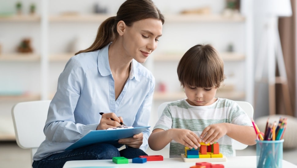 A behavioral health professional works with a child in a school setting.