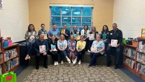 A group of Volunteers from KPMG and Partner in Outreach gather to read books at a local school.