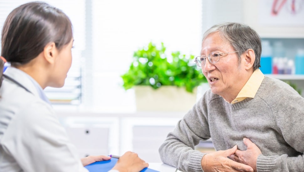 An older man talks to a doctor about his heart symptoms.