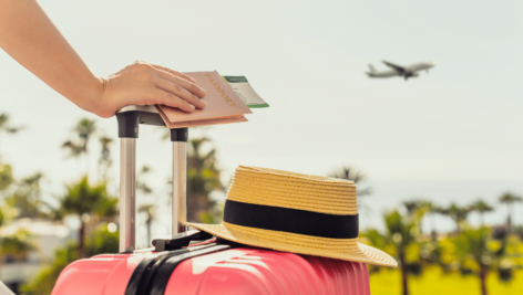 person with luggage looking at plane in sky