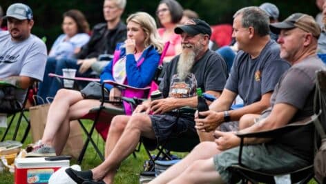 People gathered outdoors in lawn chairs enjoying summer concert at Eagleview Town Center.