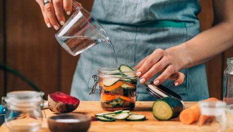 Homemade fermented vegetables. Woman pouring water in the jar with vegetables. Vegetable Fermentation Process.