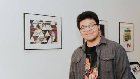 Harcum College Graphic Design student Eidan Ortiz ‘24 presents his work at the annual student exhibition.