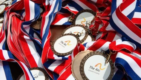 A pile of red, white and blue ribbons with The Arc of Chester County logo.