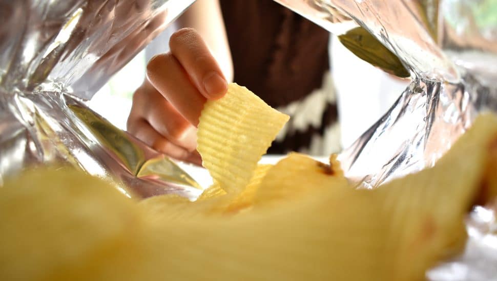 person reaching for chips in bag