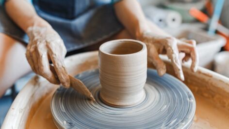 person throwing clay on potter's wheel