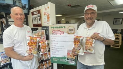 Pete Romano Jr., left and his father, Pete Romano Sr., with several bags of Herr's Romano's Original Stromboli-flavored chips.