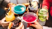 People hands toasting multicolored fancy drinks