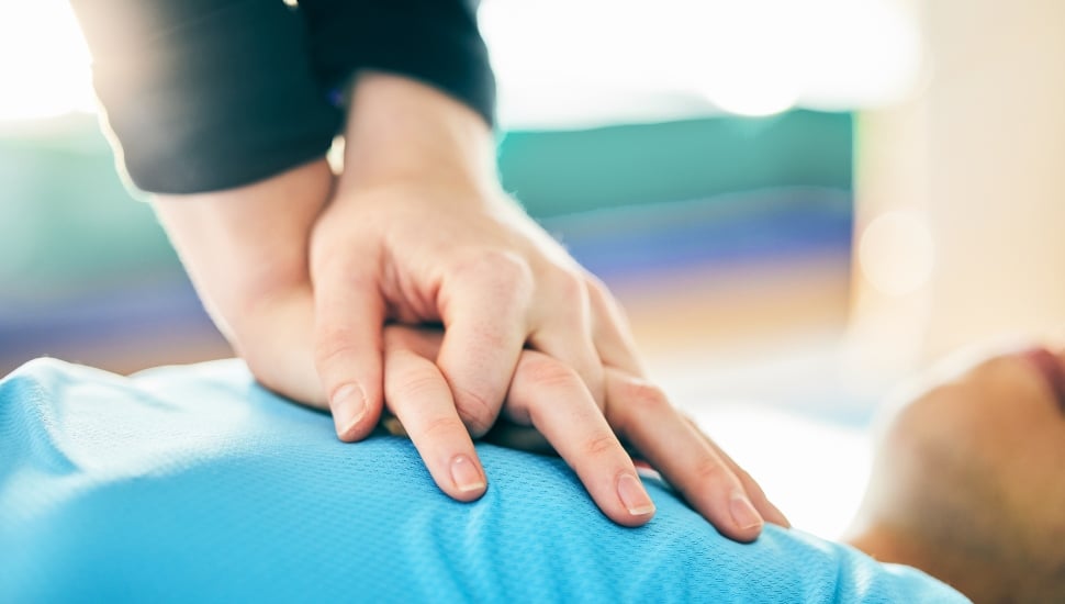 Close-up view of CPR training/hands on chest of someone lying down.
