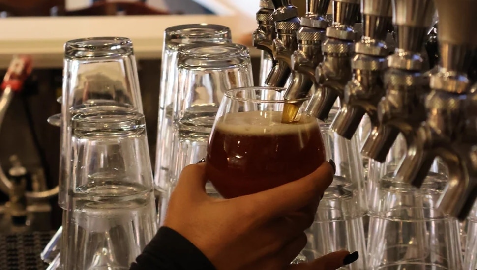 Close up of a cup underneath a beer tap.