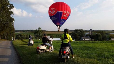 two people on scooters and a hot air balloon