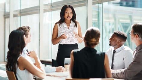 An instructor standing over a table talking to a group of students.