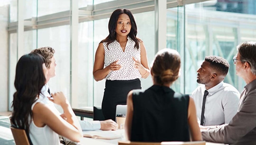 An instructor standing over a table talking to a group of students.