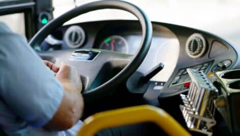 hands of a bus driver on steering wheel