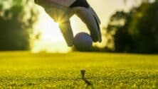 Golfer places golf ball on tee.