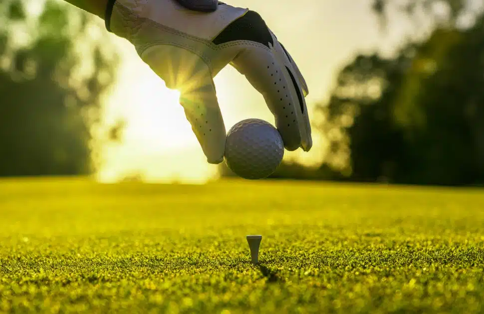 Golfer places golf ball on tee.