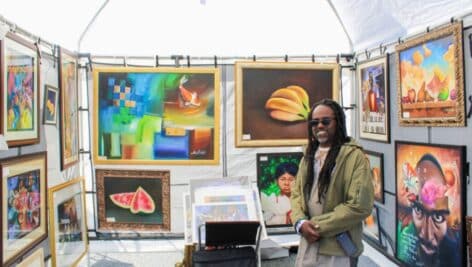 An artist under a tent showcasing a variety of his work.