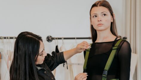 Fashion Design student fits a custom outfit on a model.