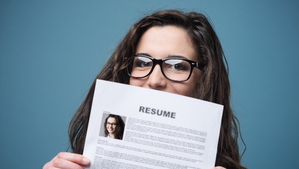 Young woman hiding behind her resume.