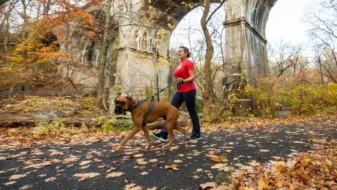 woman running on trail with dog