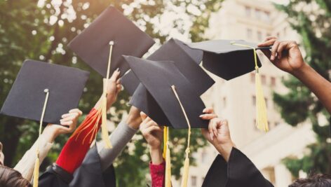 students celebrating lifting grad caps