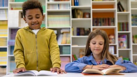 children sitting at library table reading.