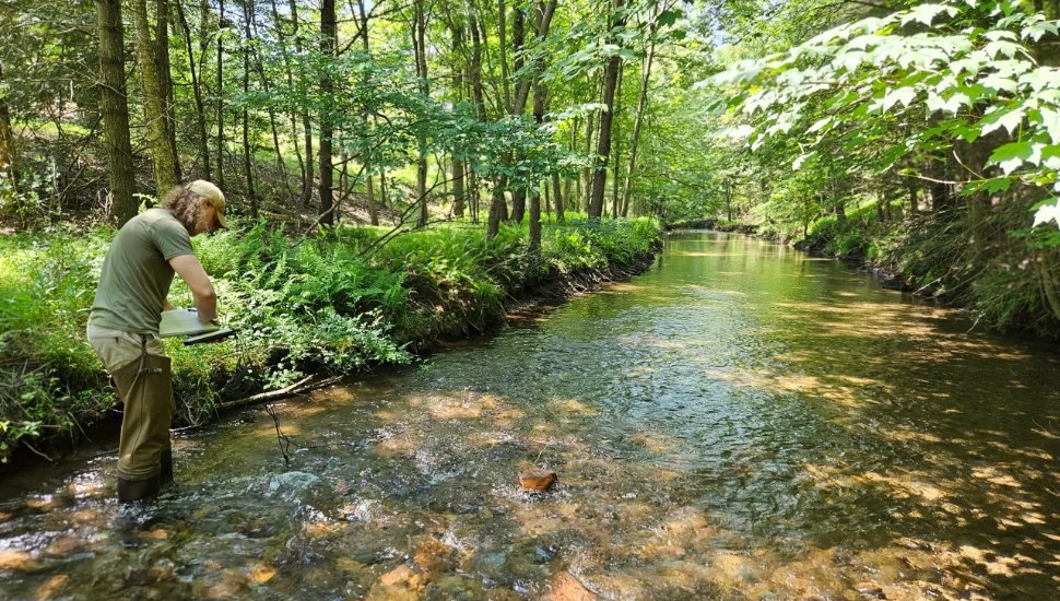 man standing in stream doing research