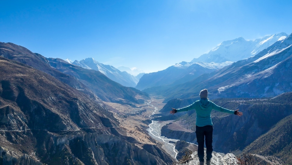 A hiker at the top of a mountain, checking off bucket list concept.