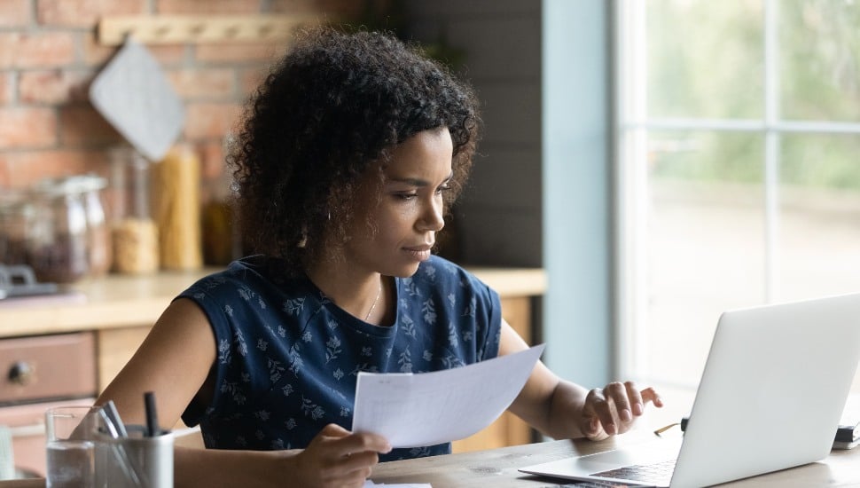 Serious millennial African American woman calculating water bill costs.