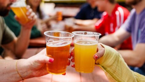 two people clinking beer cups together